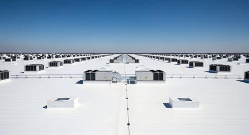 Rows of packaged rooftop HVAC units on a large distribution warehouse roof